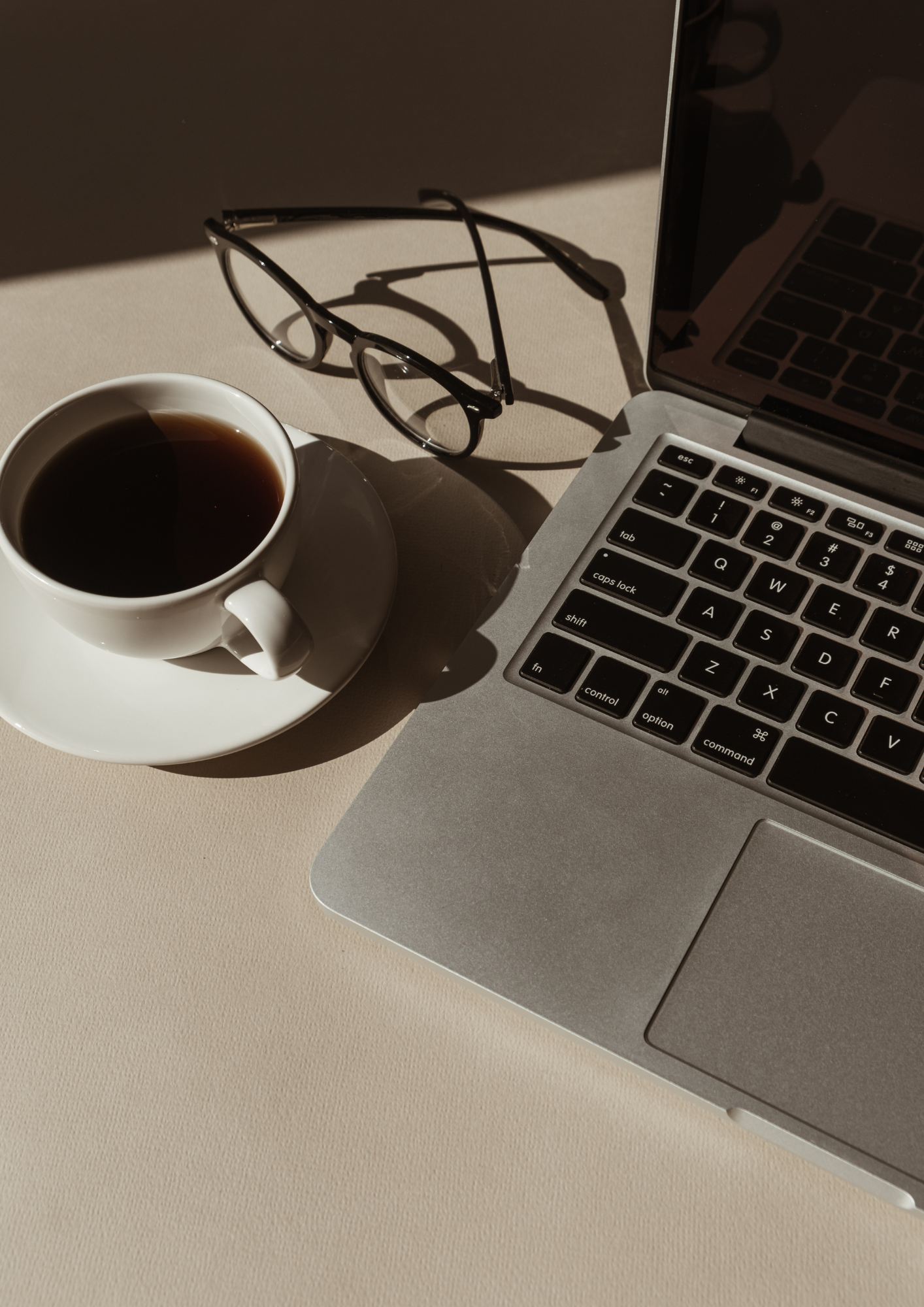 Coffee, reading glasses and a laptop in warm afternoon light
